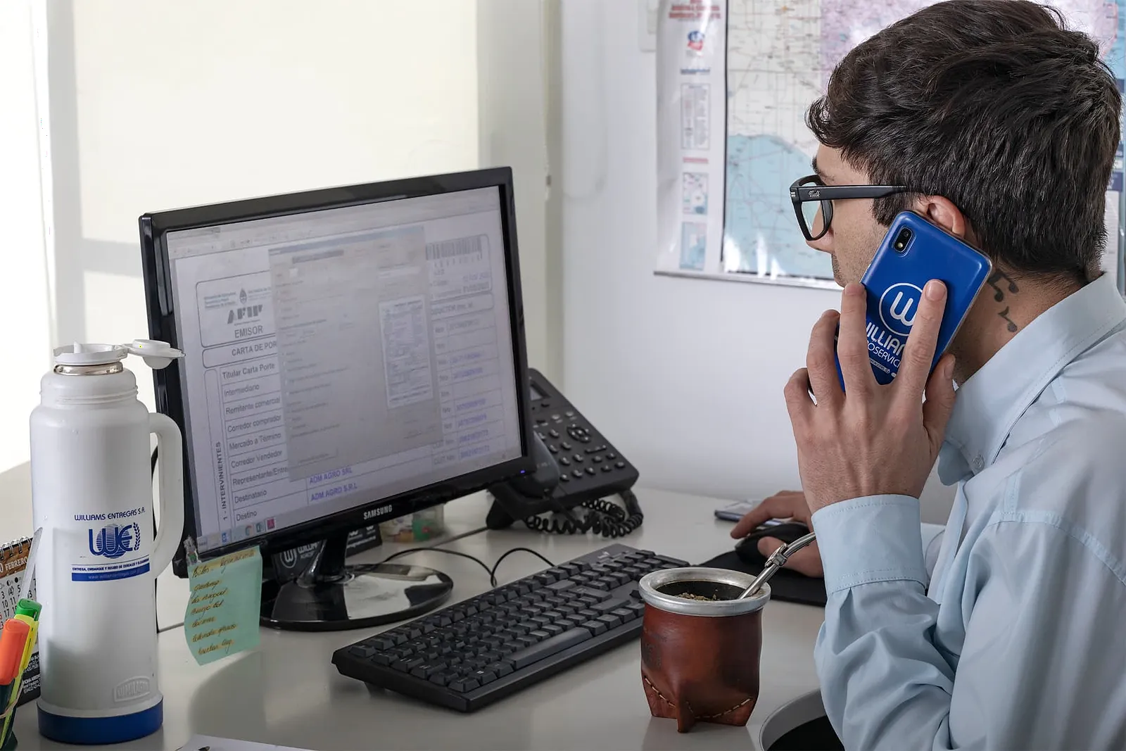 Integrante del equipo Williams Entregas consultando una operación en pantalla mientras habla por teléfono